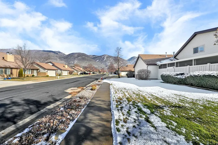 View of asphalt street featuring sidewalks, a residential view, a mountain view, and curbs