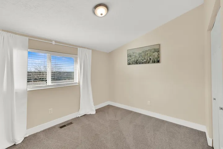 Empty room featuring lofted ceiling and carpet flooring