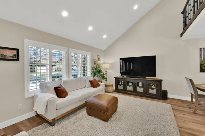 Living room featuring high vaulted ceiling, light wood-type flooring, and recessed lighting