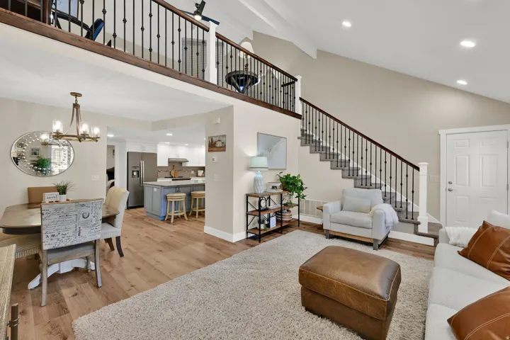 Living room with recessed lighting, stairway, light wood finished floors, a high ceiling, and a chandelier