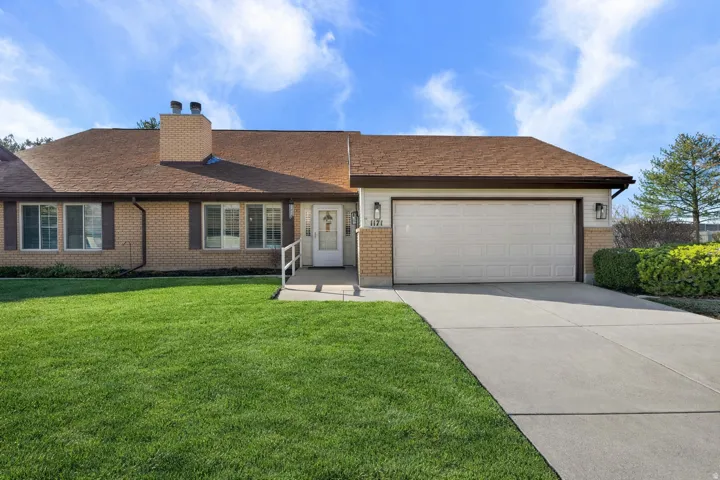 Ranch-style house with concrete driveway, a garage, a chimney, a front yard, and brick siding