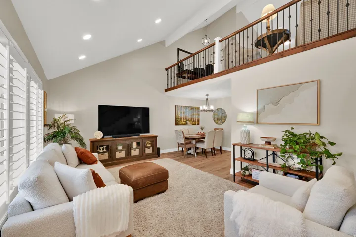 Living room with recessed lighting, light wood-style flooring, high vaulted ceiling, and a chandelier