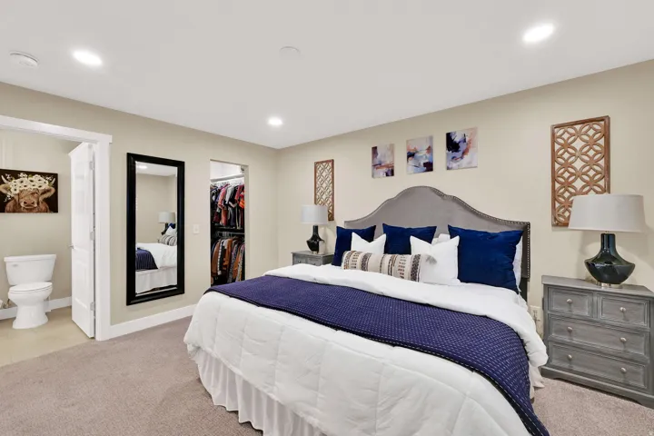 Carpeted bedroom with a walk in closet, ensuite bath, and recessed lighting