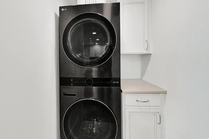 Laundry room featuring stacked washer and clothes dryer and cabinet space