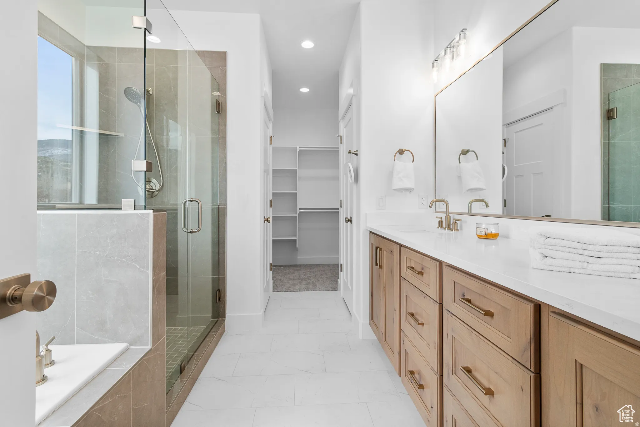 Full bath with a shower stall, vanity, a bath, a walk in closet, and recessed lighting