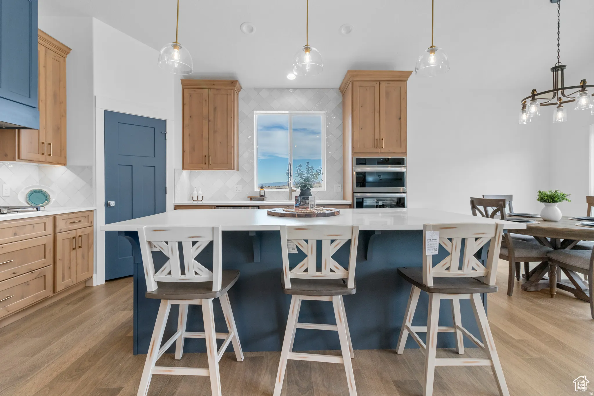 Kitchen with dual tone cabinetry, decorative backsplash, a breakfast bar, a kitchen island, and light wood finished floors