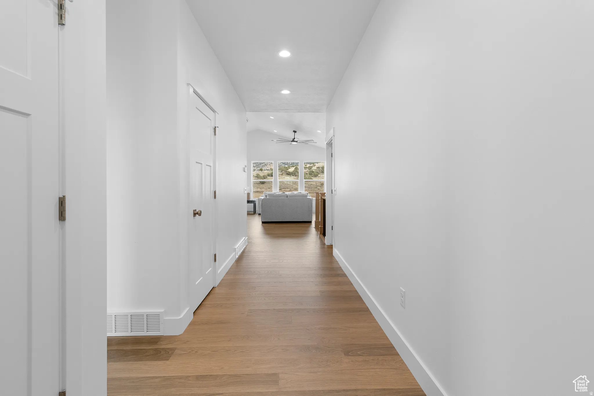 Hallway with recessed lighting, light wood-style flooring, and vaulted ceiling