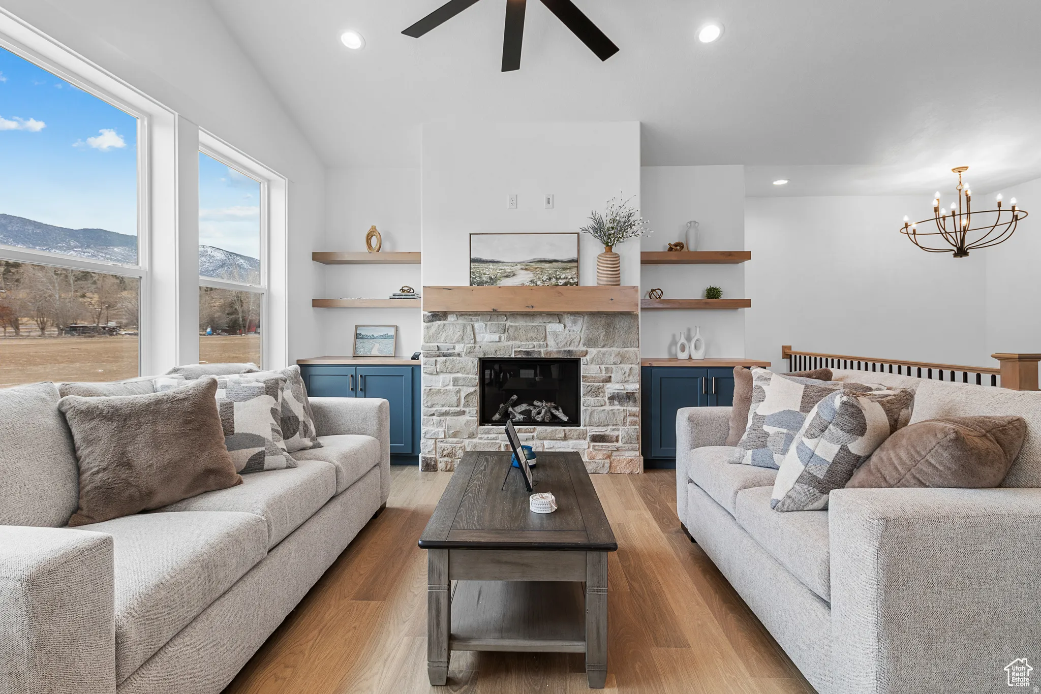 Living area featuring ceiling fan, light wood-type flooring, a fireplace, a chandelier, and a mountain view