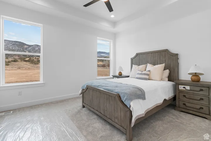 Carpeted bedroom with a mountain view and ceiling fan