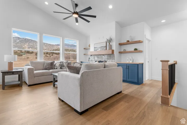 Living area featuring a mountain view, recessed lighting, light wood-style flooring, a ceiling fan, and vaulted ceiling