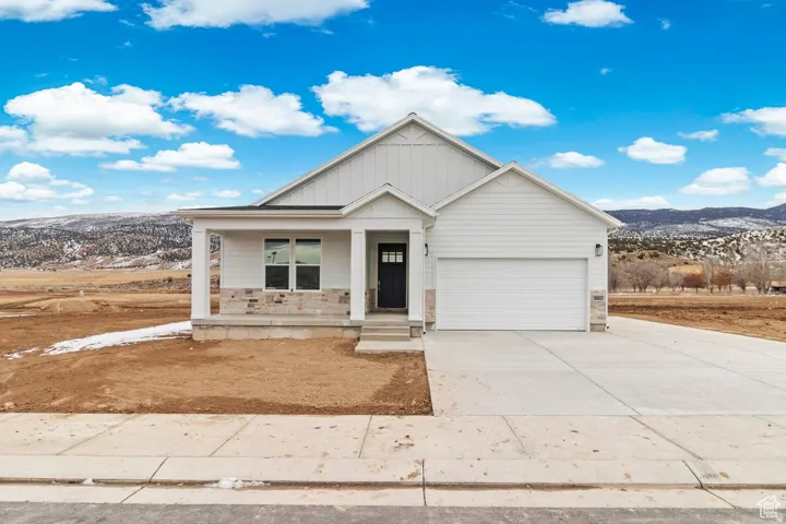 View of front of house with a mountain view, a porch, driveway, stone siding, and board and batten siding