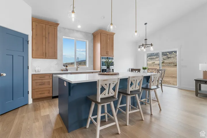 Dual tone kitchen with dual tone cabinetry, a kitchen breakfast bar, pendant lighting, tasteful backsplash, and a kitchen island