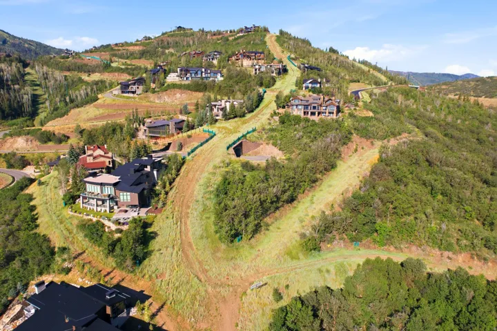Hillside property featuring multiple residences, extensive surrounding greenery, and winding pathways