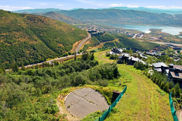 Mountainous terrain with expansive green hillsides, a winding road, and distant body of water