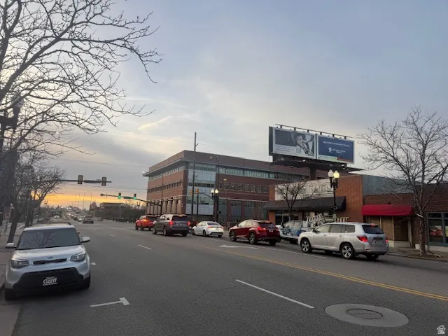 View of asphalt road with traffic lights, curbs, sidewalks, and street lighting