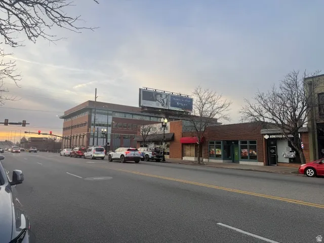 View of asphalt road featuring sidewalks, traffic lights, and curbs