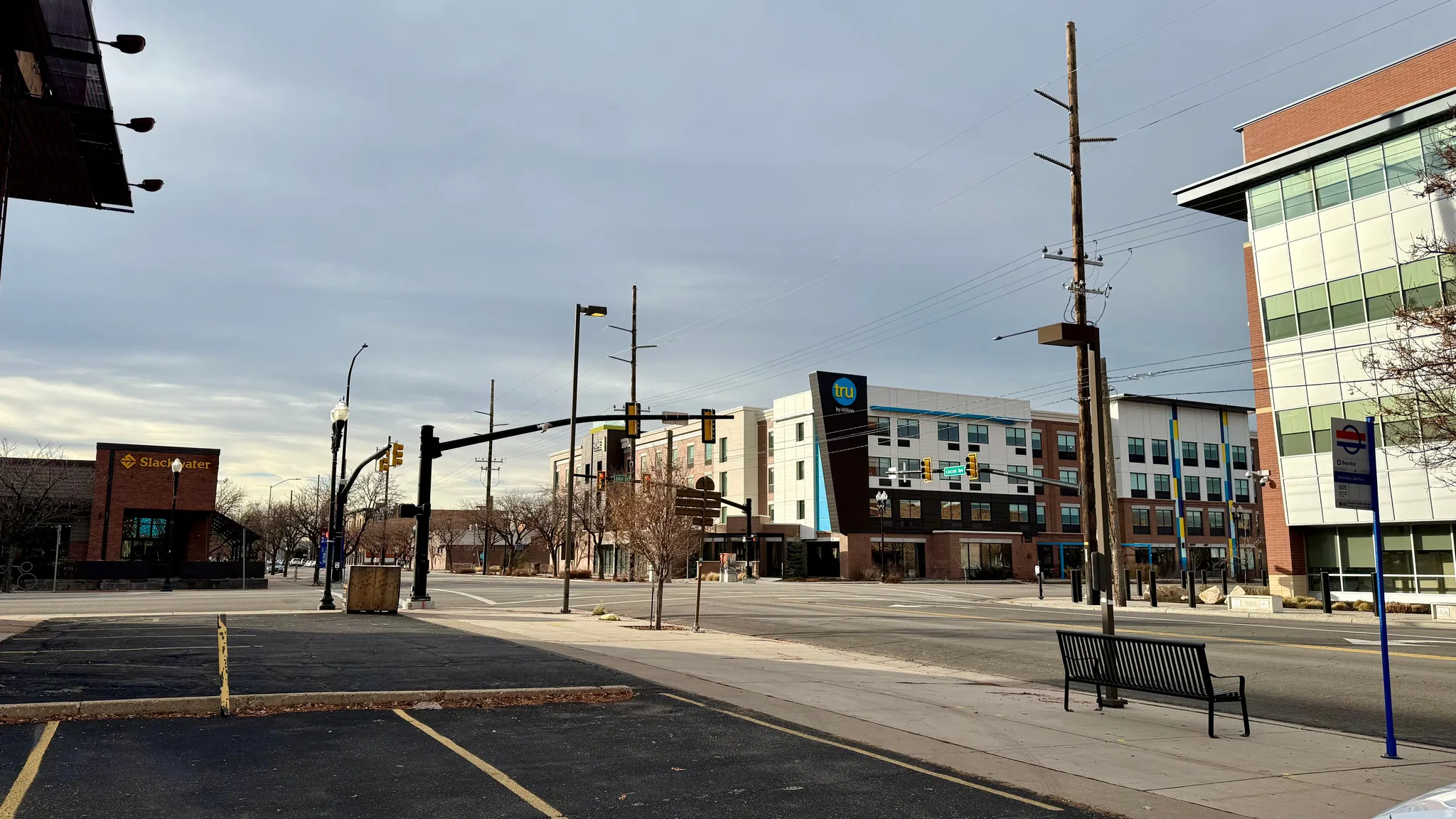 View of asphalt road with traffic lights, curbs, sidewalks, and street lighting