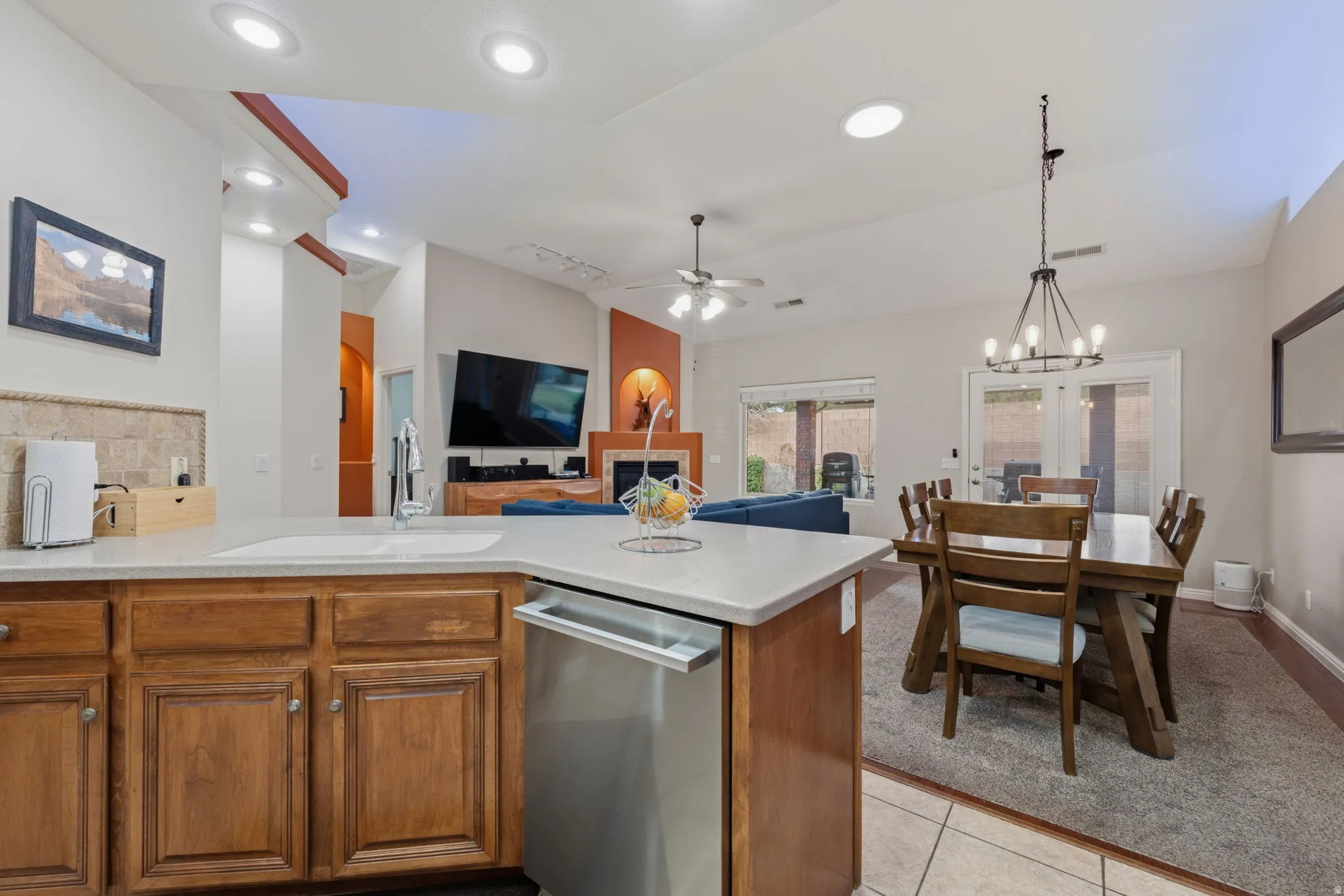 Kitchen featuring wood finish cabinets, dishwasher, light tile patterned floors, a ceiling fan, and suspended lighting