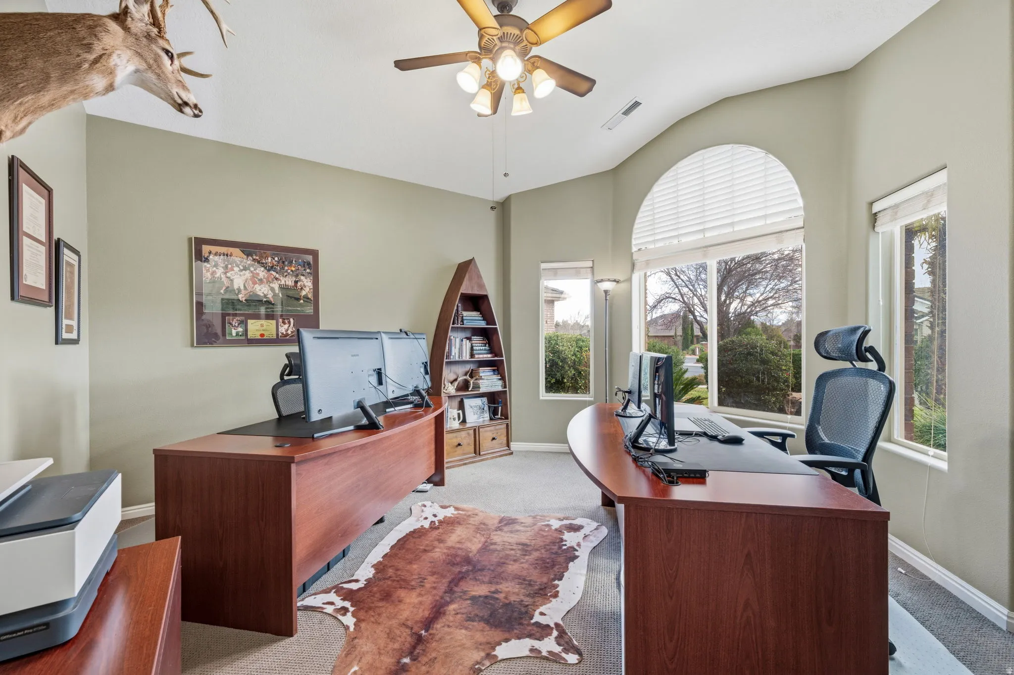 Carpeted home office with ceiling fan and baseboards