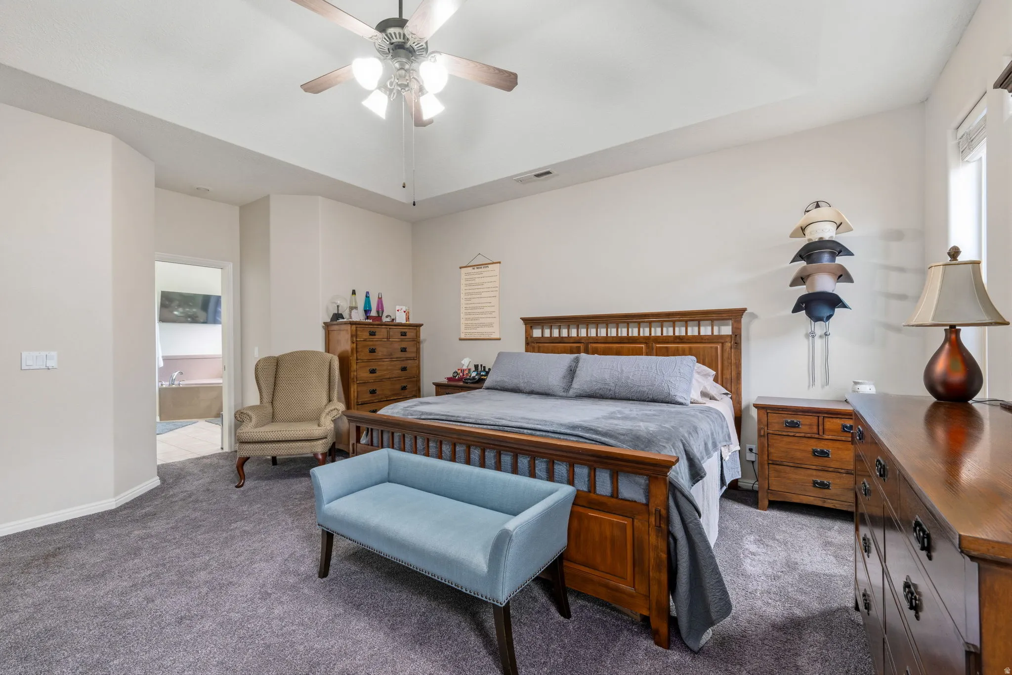 Carpeted bedroom with ensuite bath and a ceiling fan