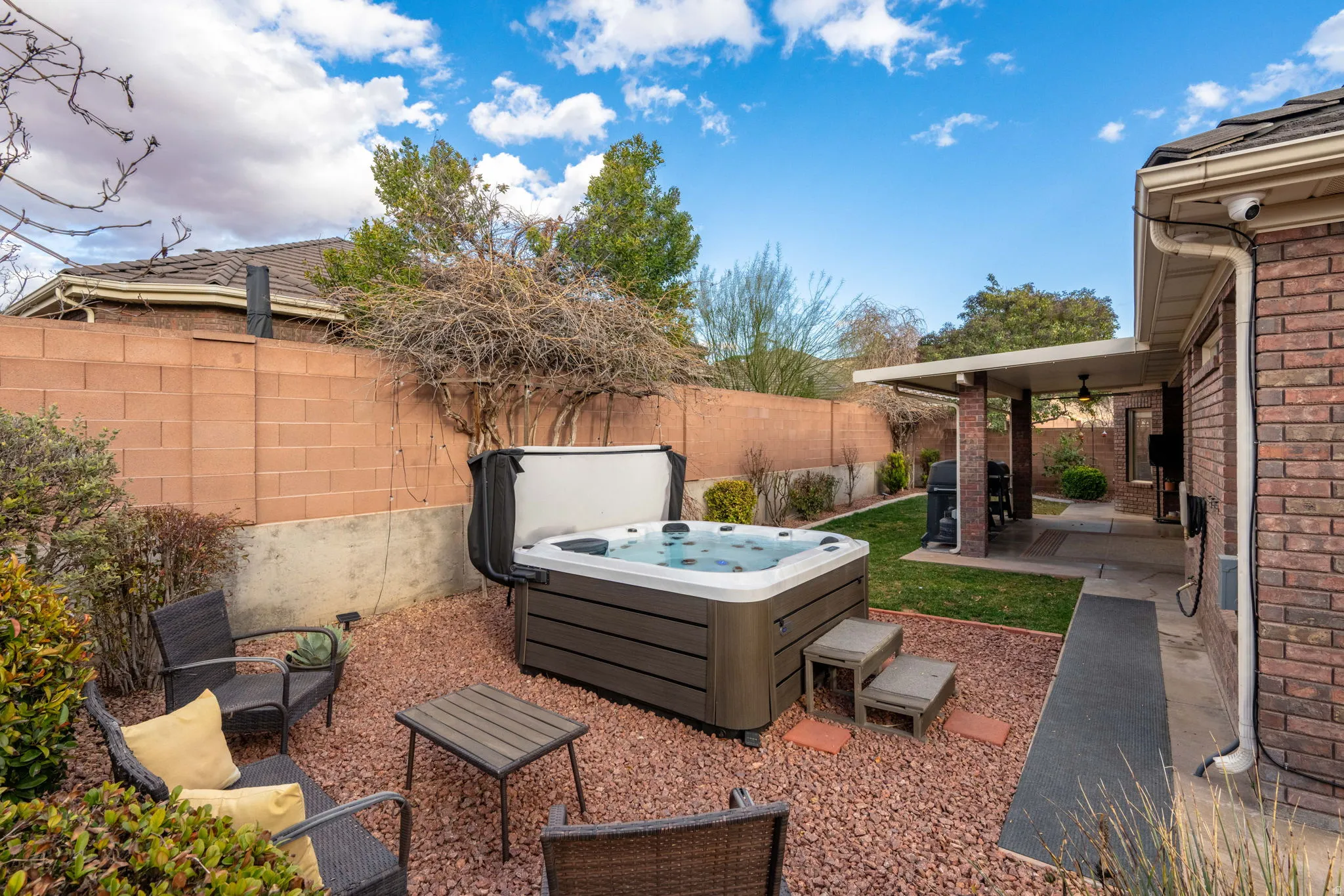 Fenced backyard with a patio area, grilling area, and a hot tub