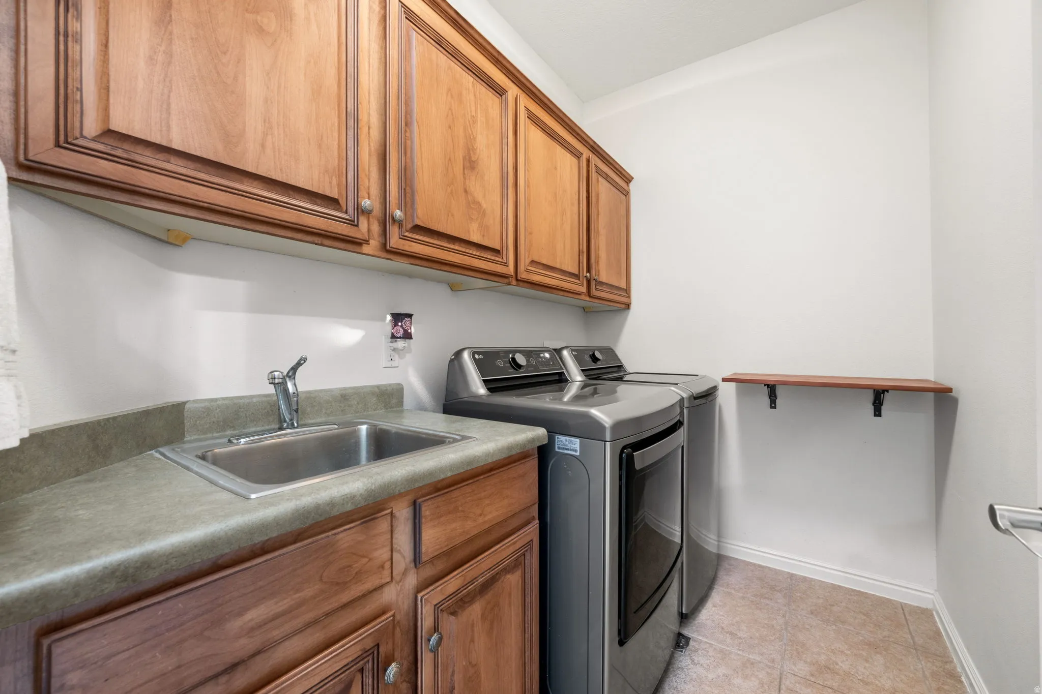 Laundry area with separate washer and dryer, cabinet space, and light tile patterned flooring