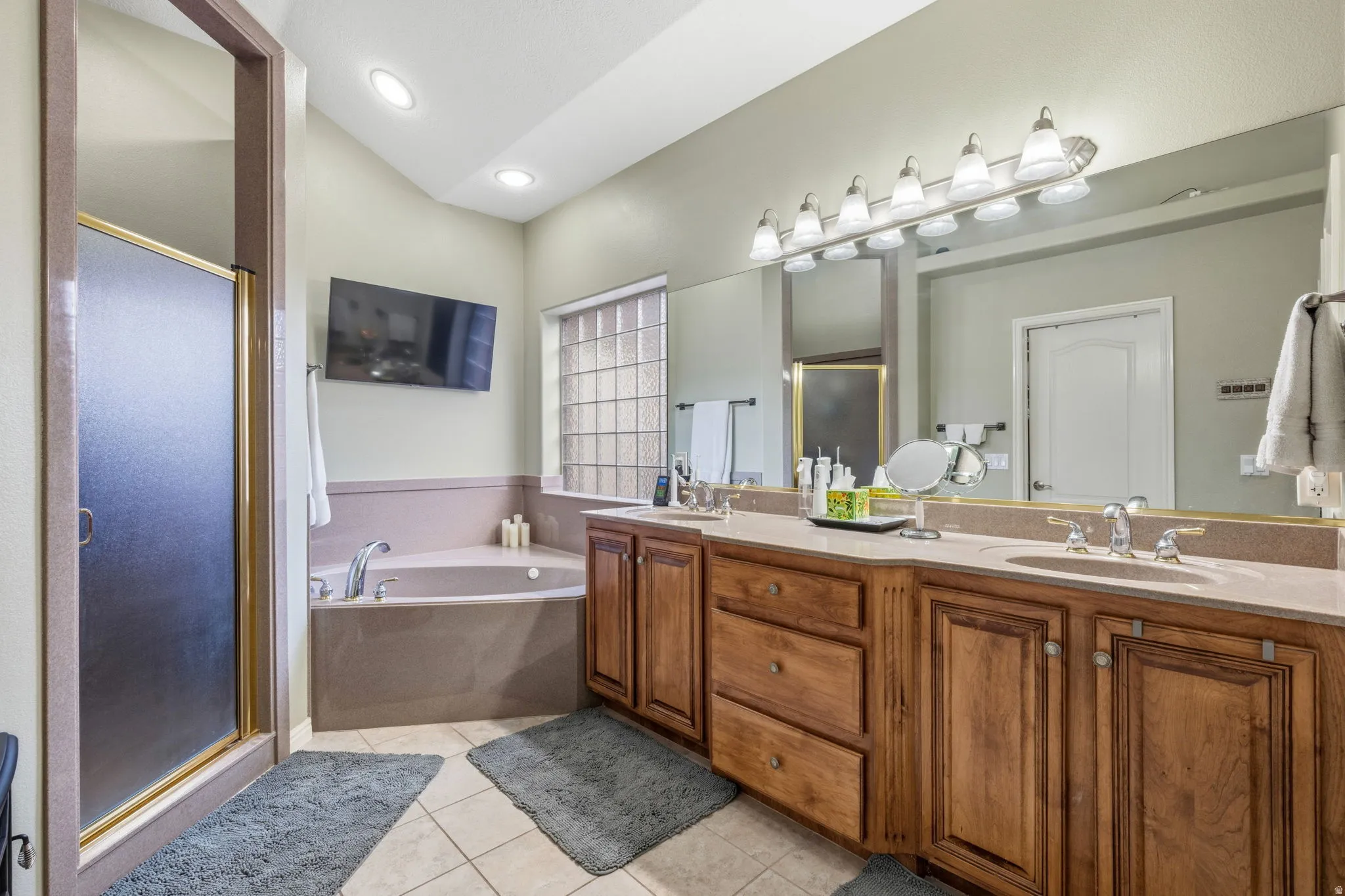 Bathroom with double vanity, a stall shower, light tile patterned floors, and a bath