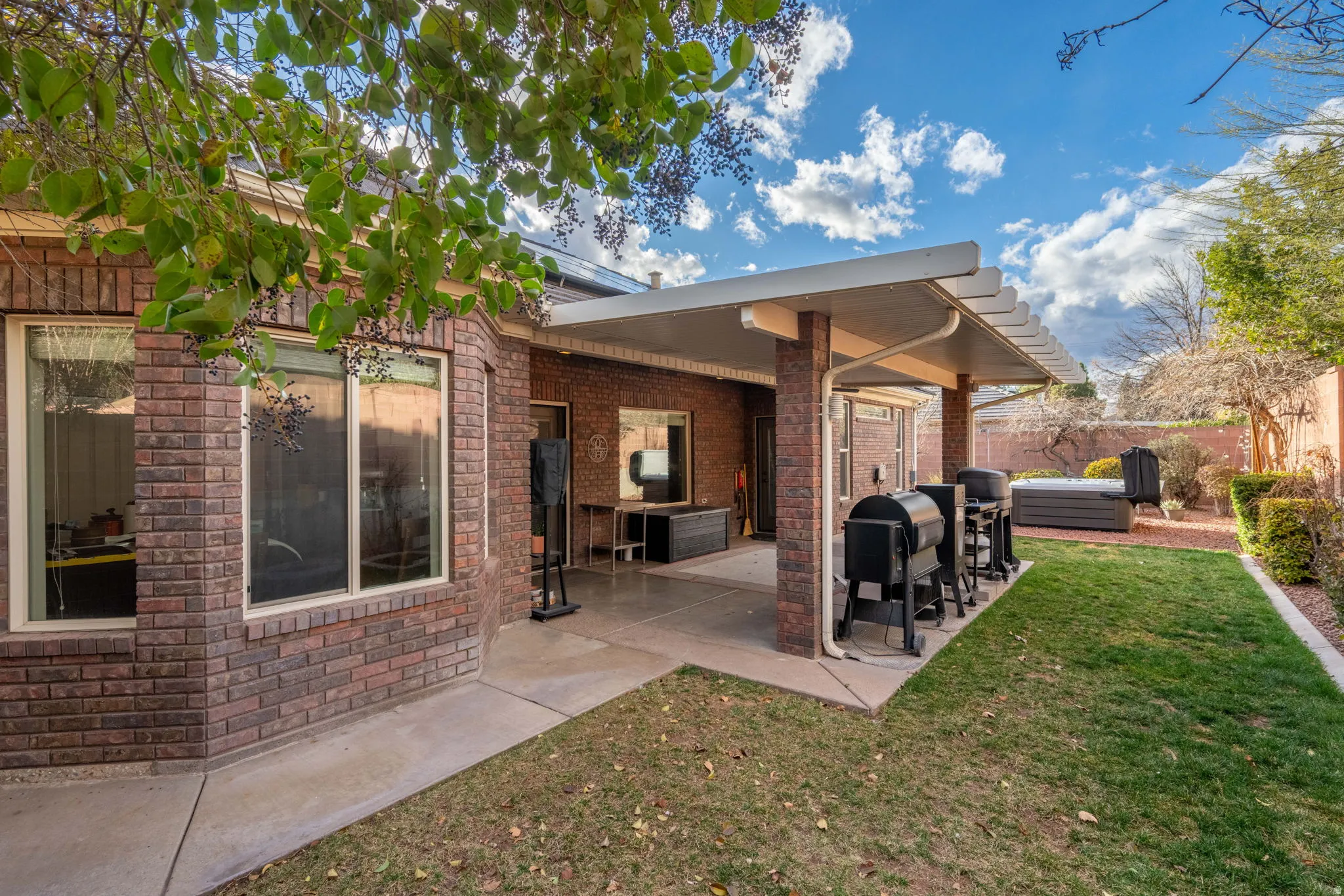 Back of house with a patio, a fenced backyard, brick siding, and a jacuzzi