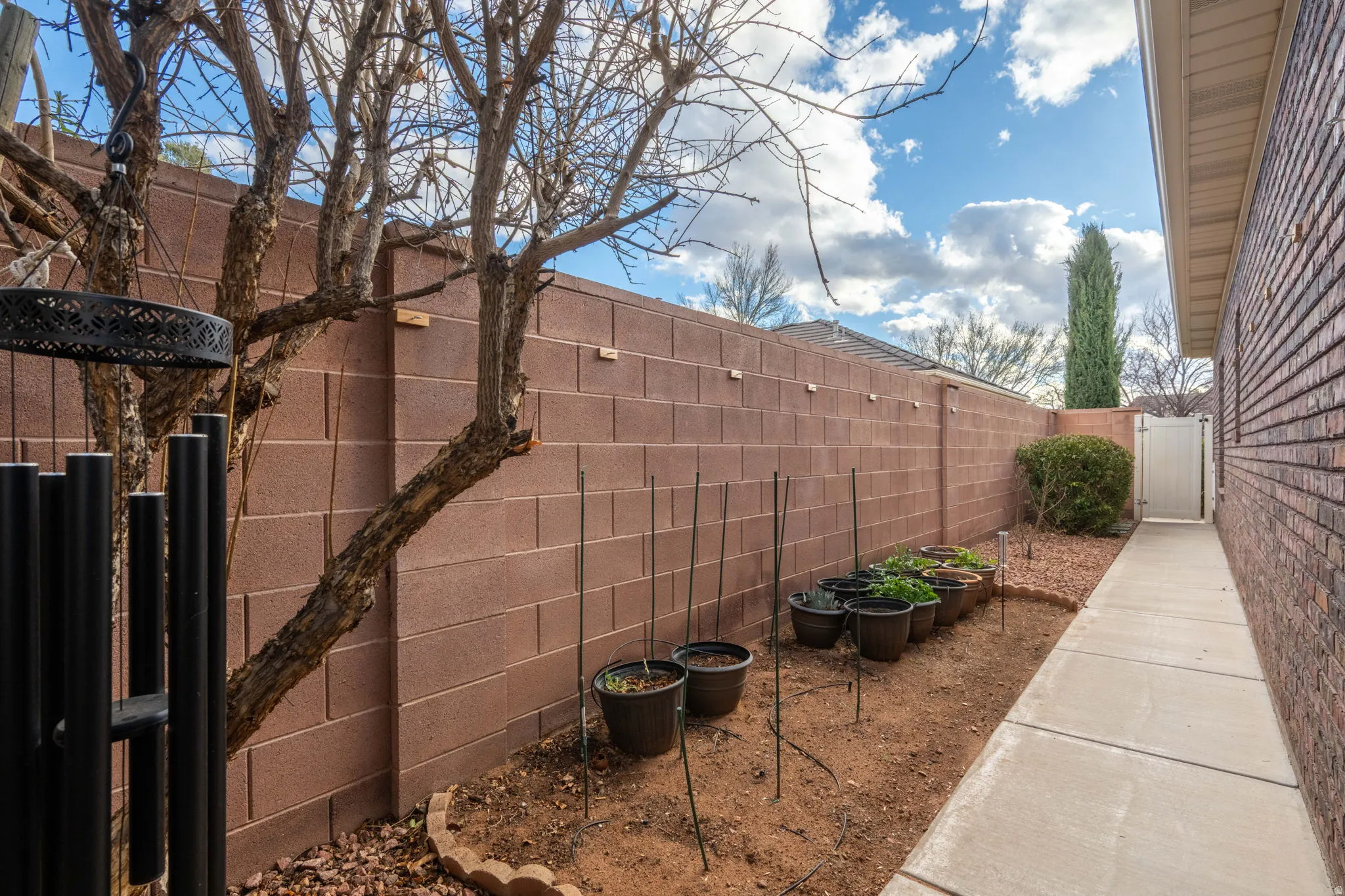Fenced backyard featuring a vegetable garden and a gate