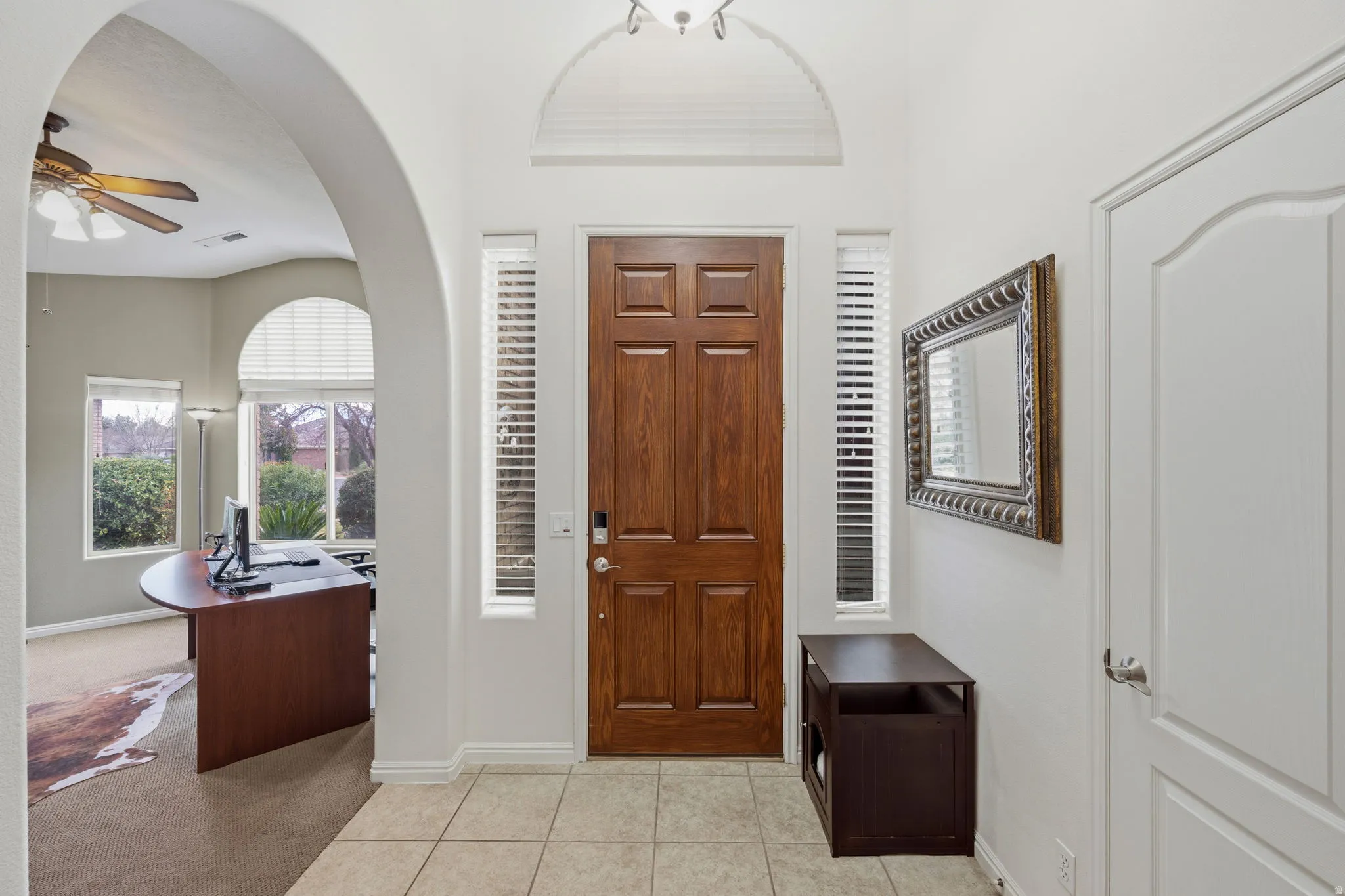Entrance foyer featuring a ceiling fan, light tile patterned floors, and light carpet