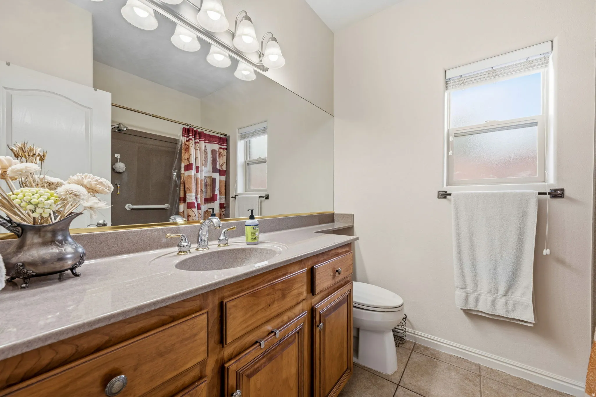 Full bath with vanity, light tile patterned floors, and a shower with curtain