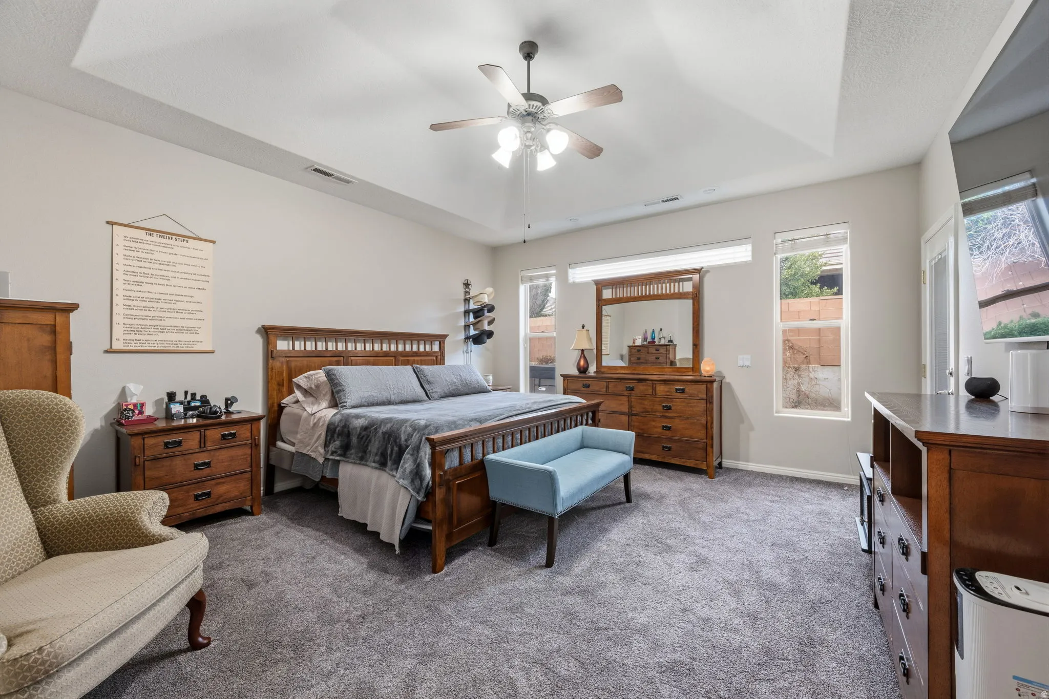 Bedroom with a raised ceiling, carpet floors, and ceiling fan