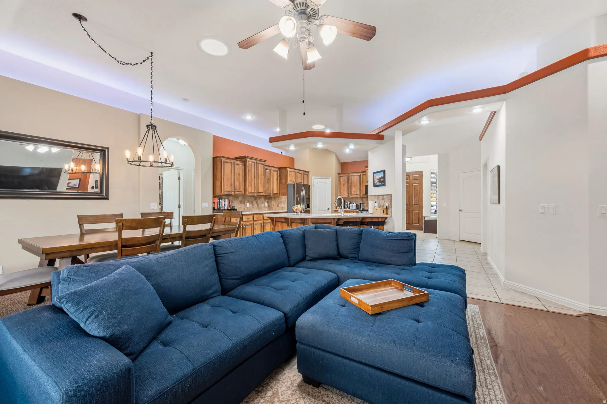 Living room with a ceiling fan, light wood-style floors, hanging lights, and arched walkways