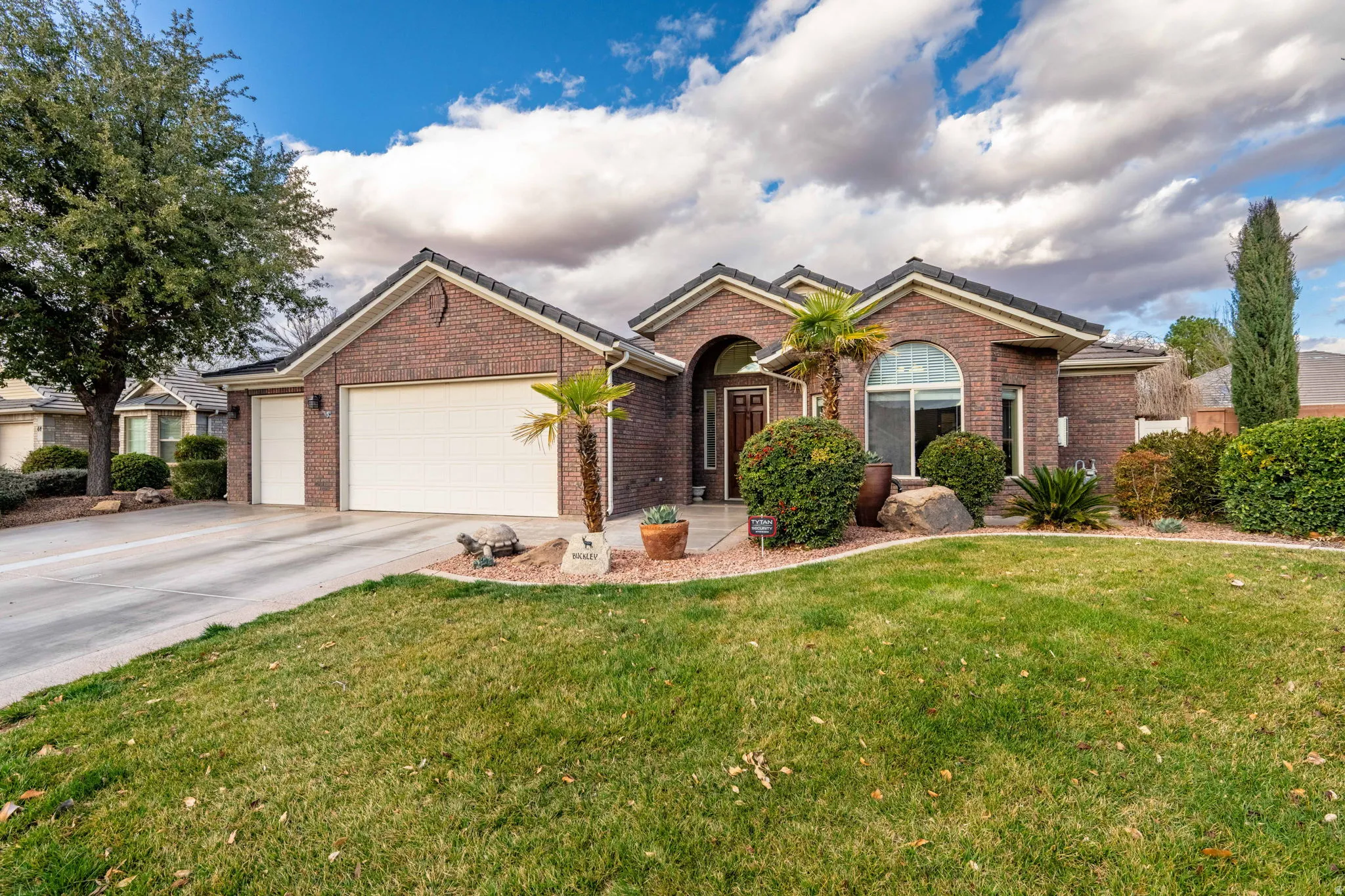 Ranch-style home featuring a garage, driveway, brick siding, and a front lawn