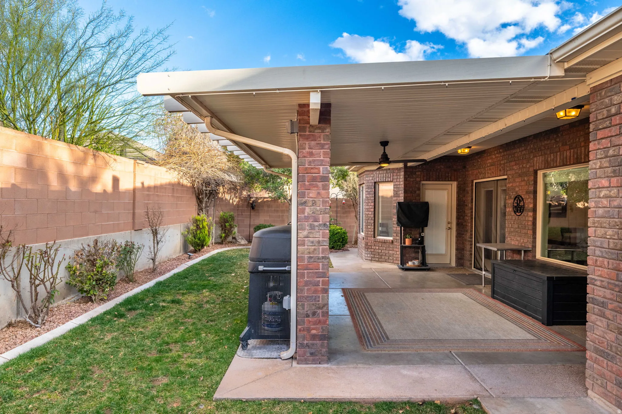 Fenced backyard with a patio, a ceiling fan, and area for grilling