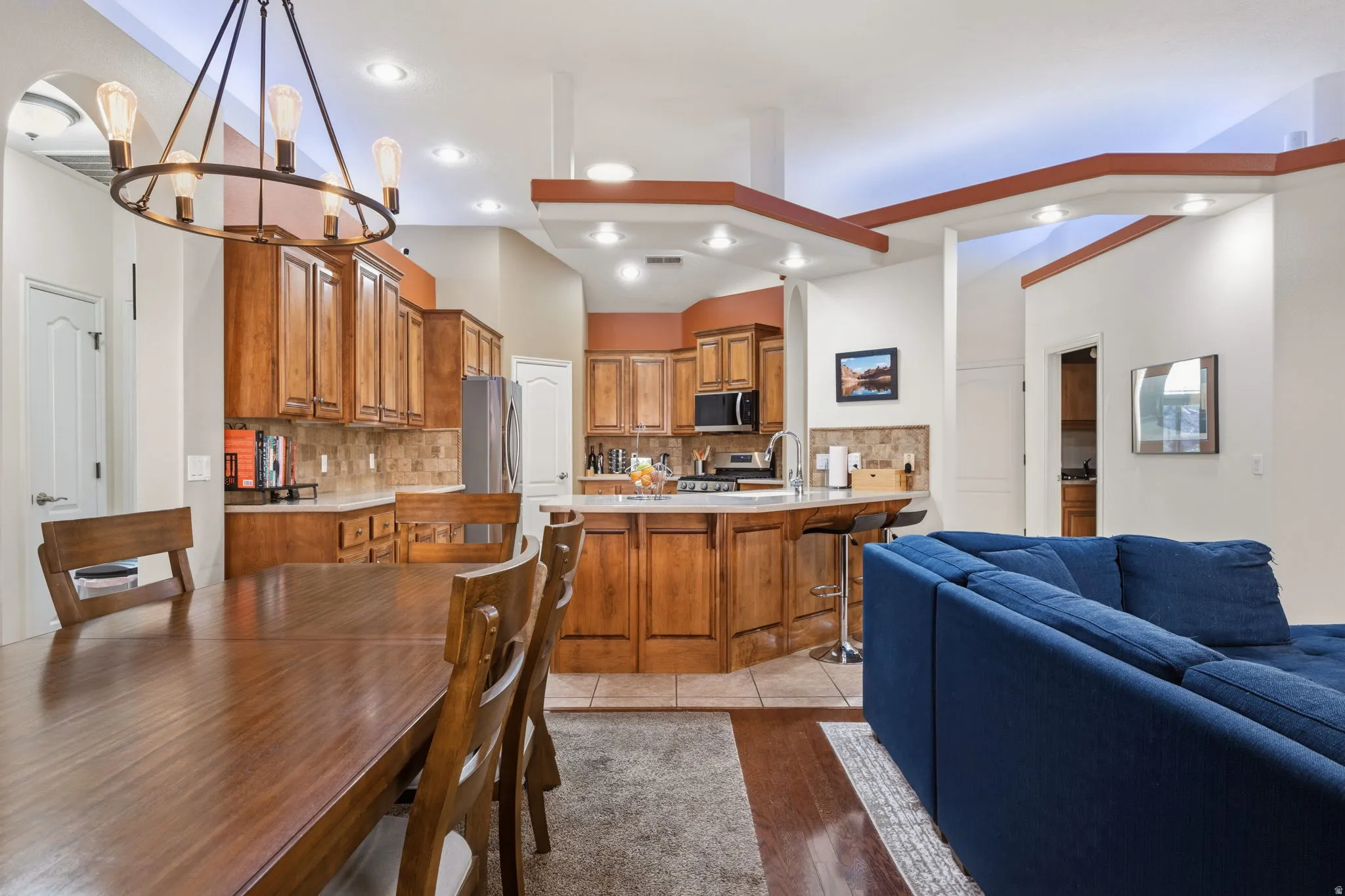 Kitchen with open floor plan, wood finish cabinets, tasteful backsplash, a kitchen bar, and stainless steel appliances