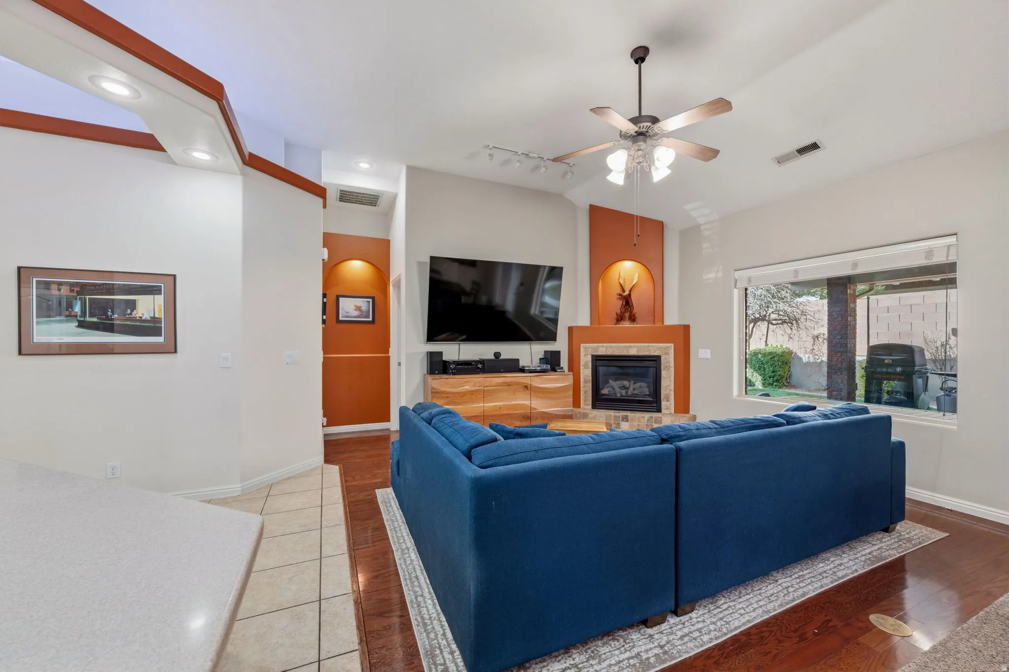 Living area featuring lofted ceiling, a fireplace, arched walkways, a ceiling fan, and track lighting