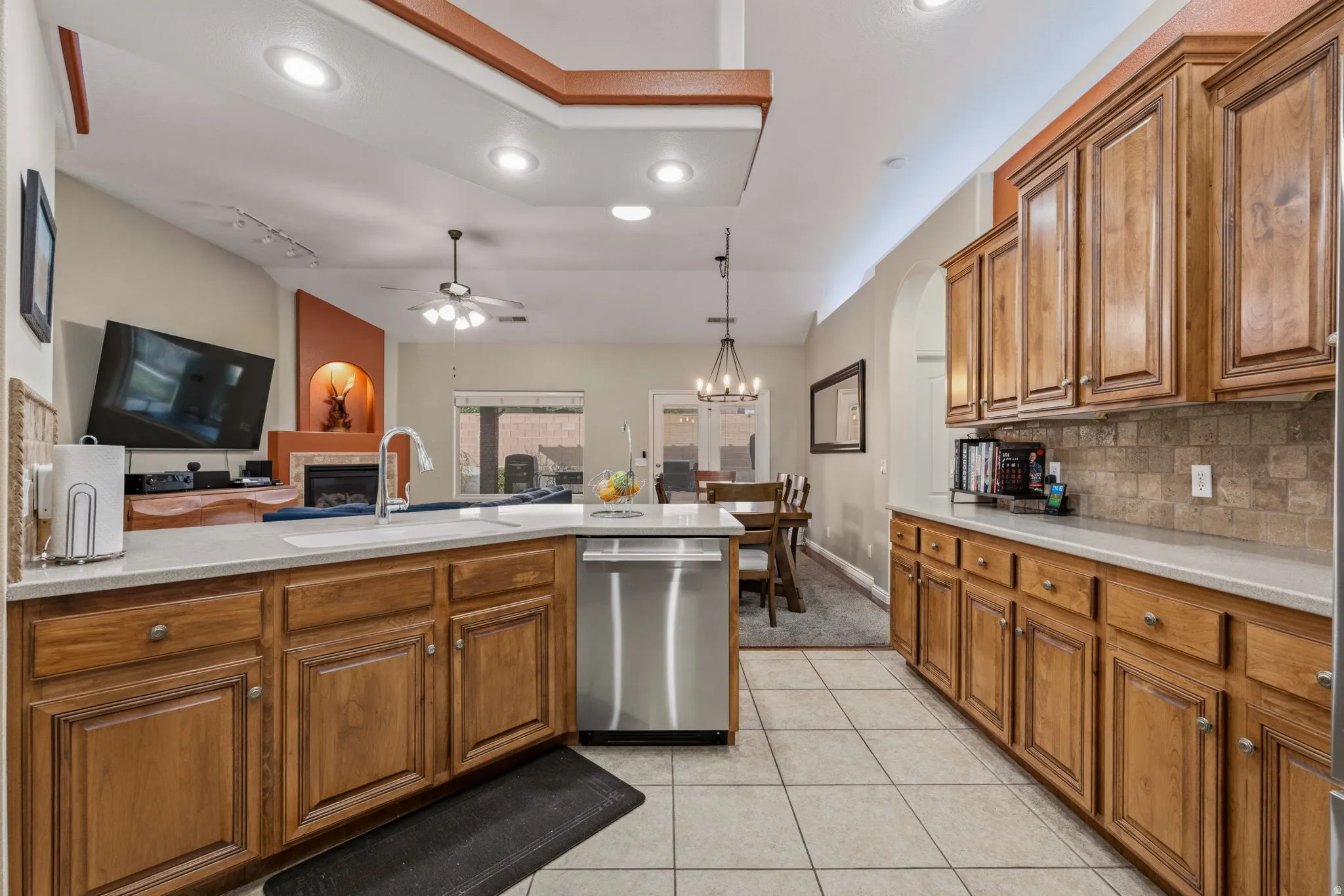 Kitchen featuring wood finish cabinets, open floor plan, dishwasher, and light tile patterned floors