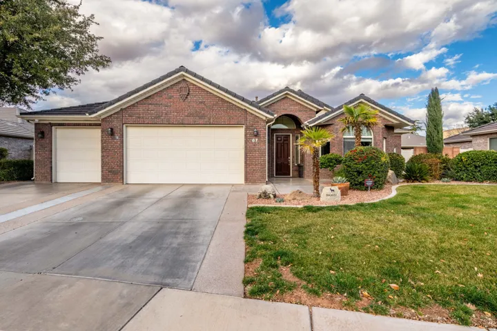 Single story home with a garage, concrete driveway, a front lawn, and brick siding
