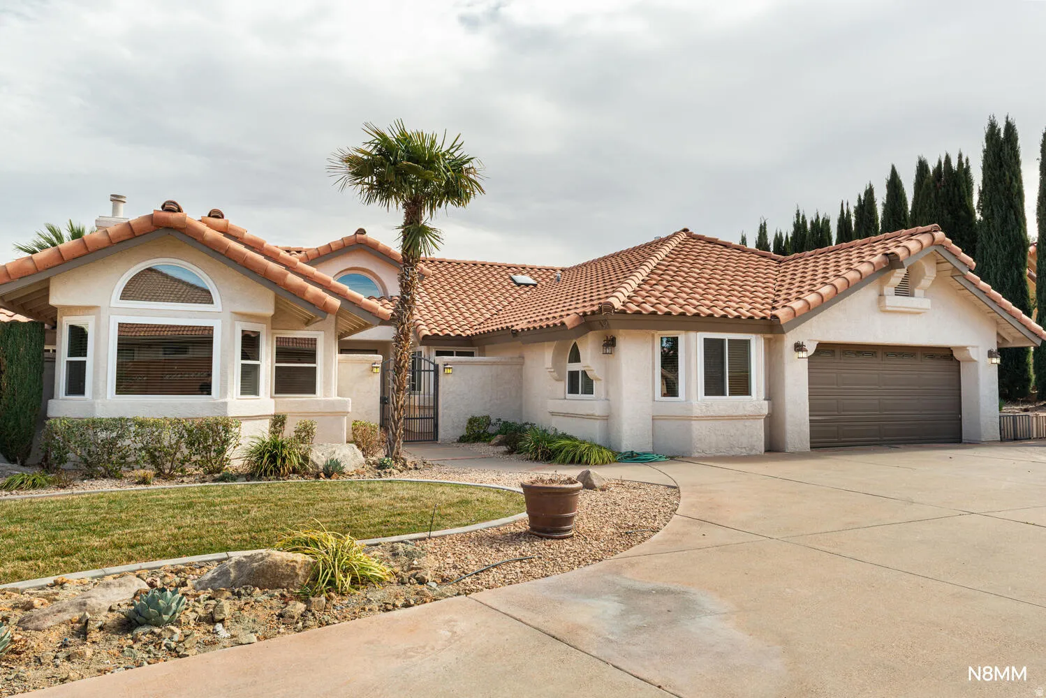 Mediterranean / Spanish house featuring stucco siding, concrete driveway, an attached garage, a gate, and a tile roof