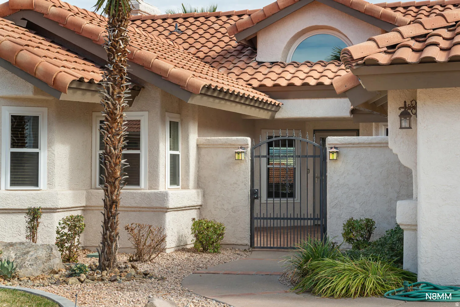View of exterior entry featuring a gate, a tile roof, and stucco siding