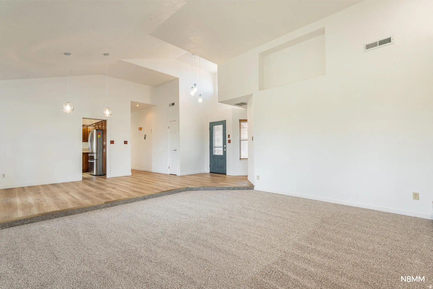 Great room featuring light carpet and vaulted ceiling