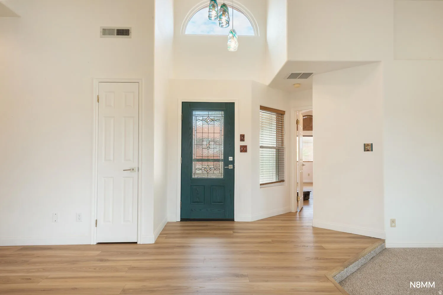 Entrance foyer with light wood-type flooring and a high ceiling