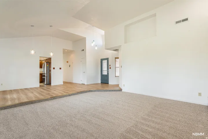 Great room featuring light carpet and vaulted ceiling