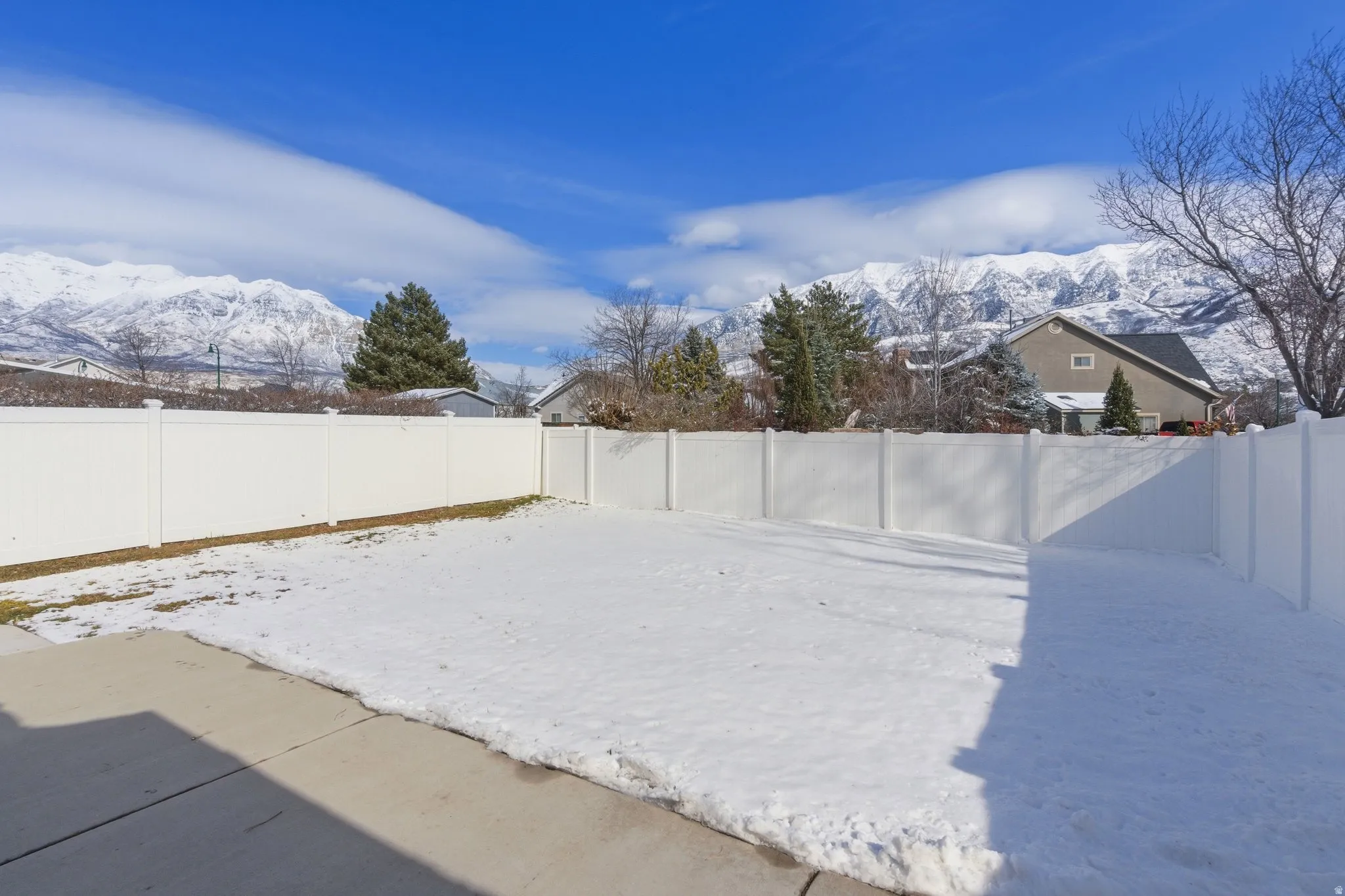 Snowy yard with a fenced backyard and a mountain view