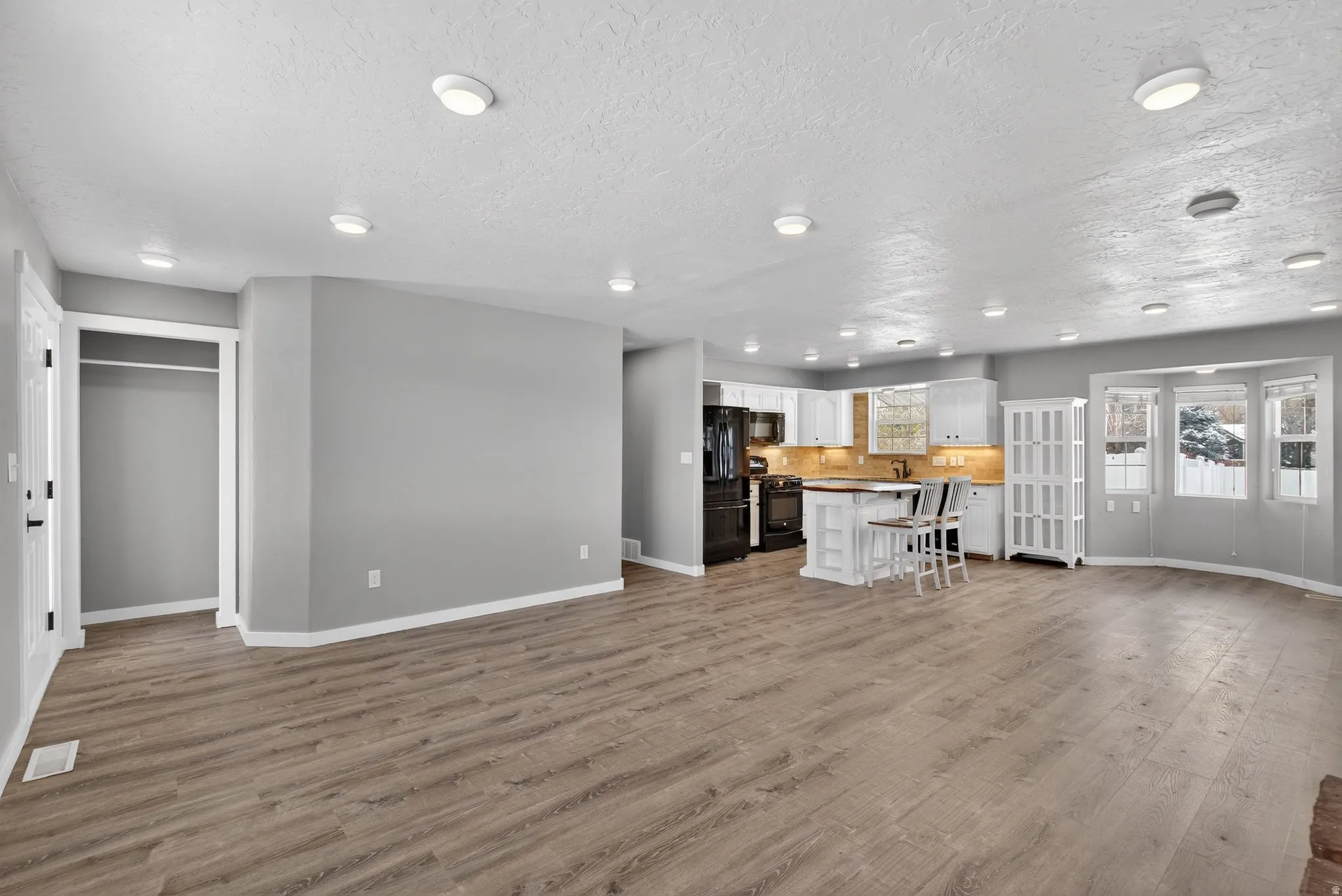 Living area featuring light wood-type flooring, a textured ceiling, and recessed lighting