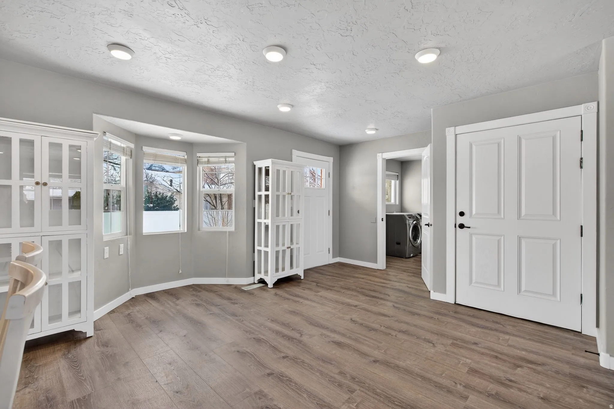 Entrance foyer featuring washer and dryer, plenty of natural light, wood finished floors, and a textured ceiling