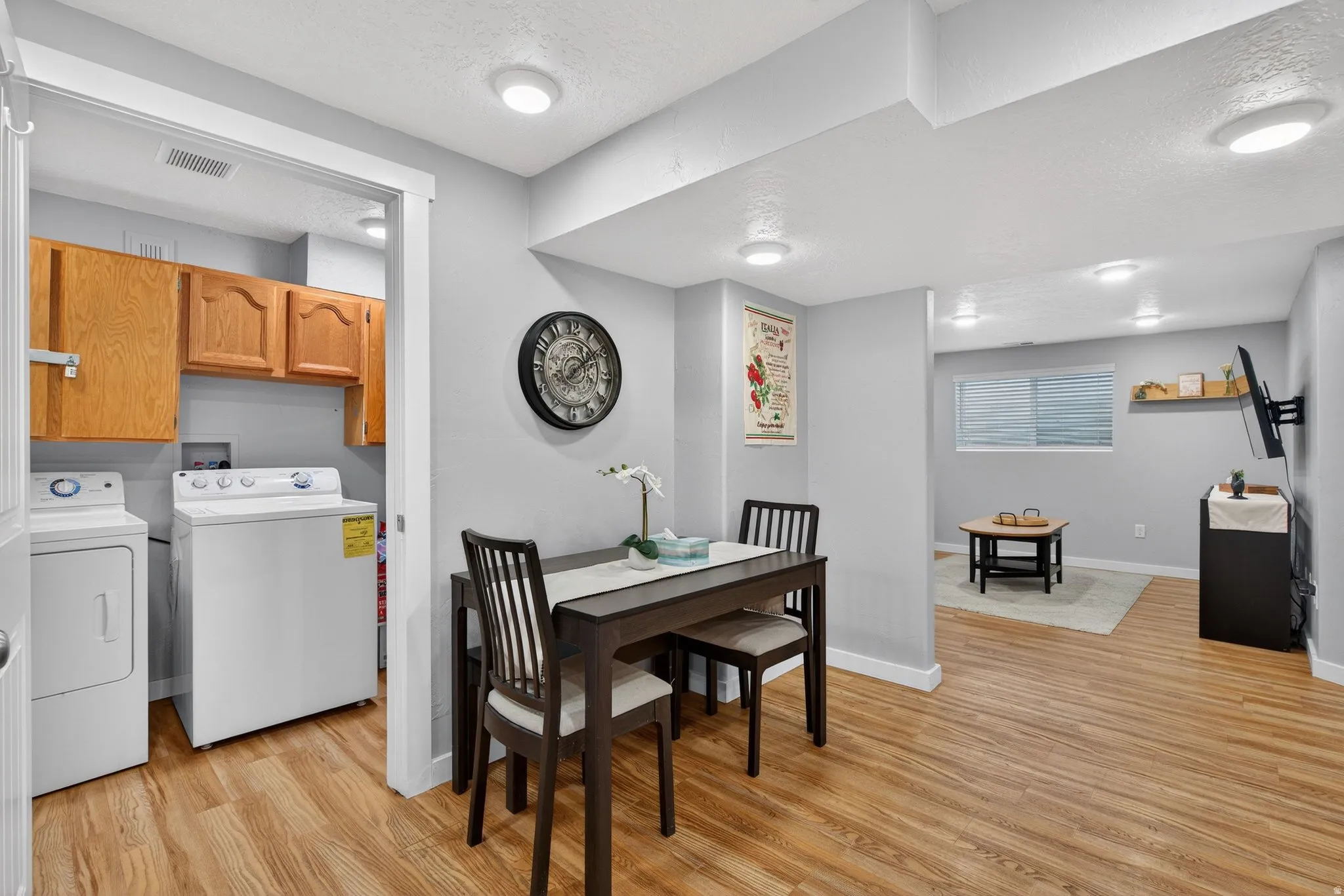 Dining room featuring a textured ceiling, light wood-style floors, and independent washer and dryer