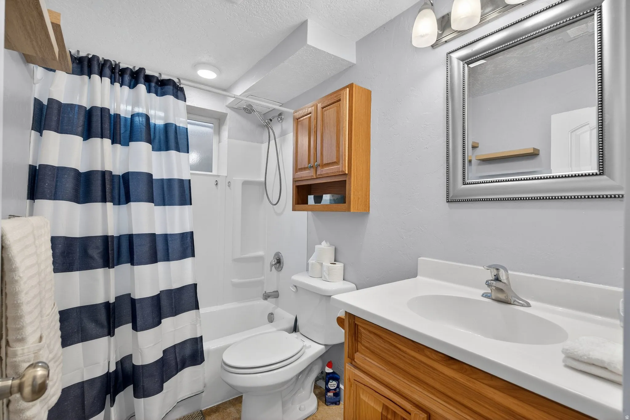Full bathroom with vanity, a textured ceiling, and shower / bath combo with shower curtain