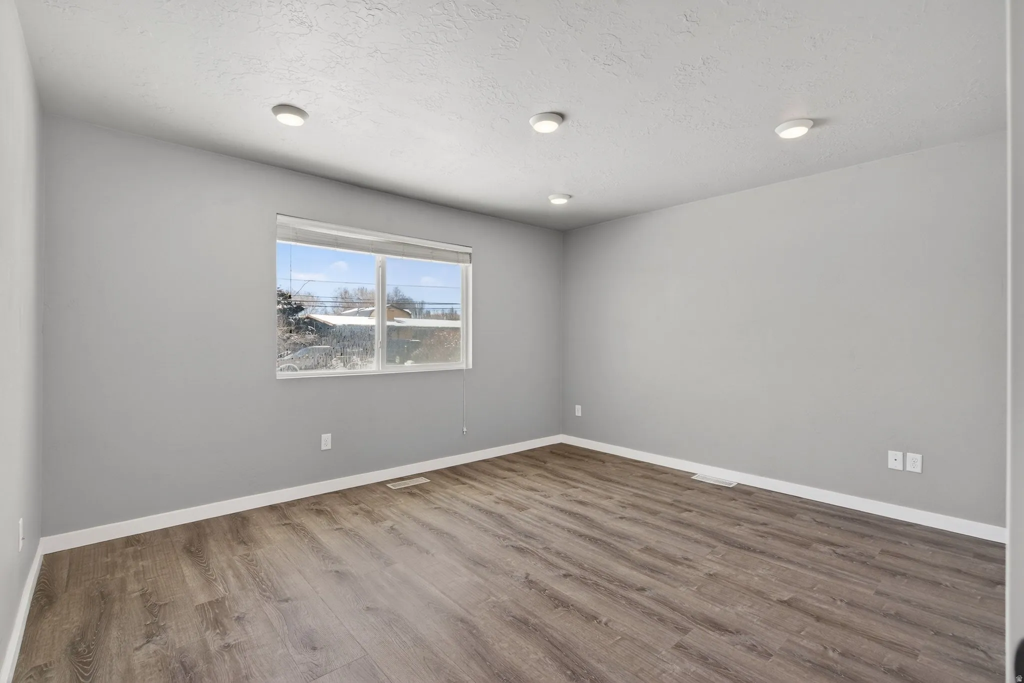 Unfurnished room with wood finished floors and a textured ceiling